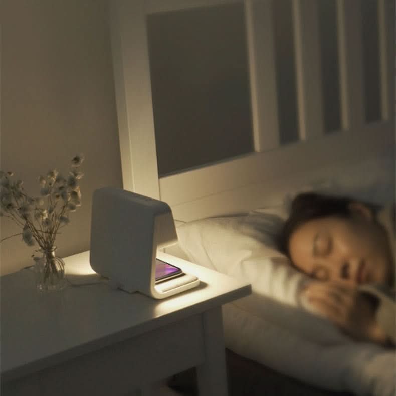 White LED bedside lamp glowing softly next to bed with alarm clock display visible