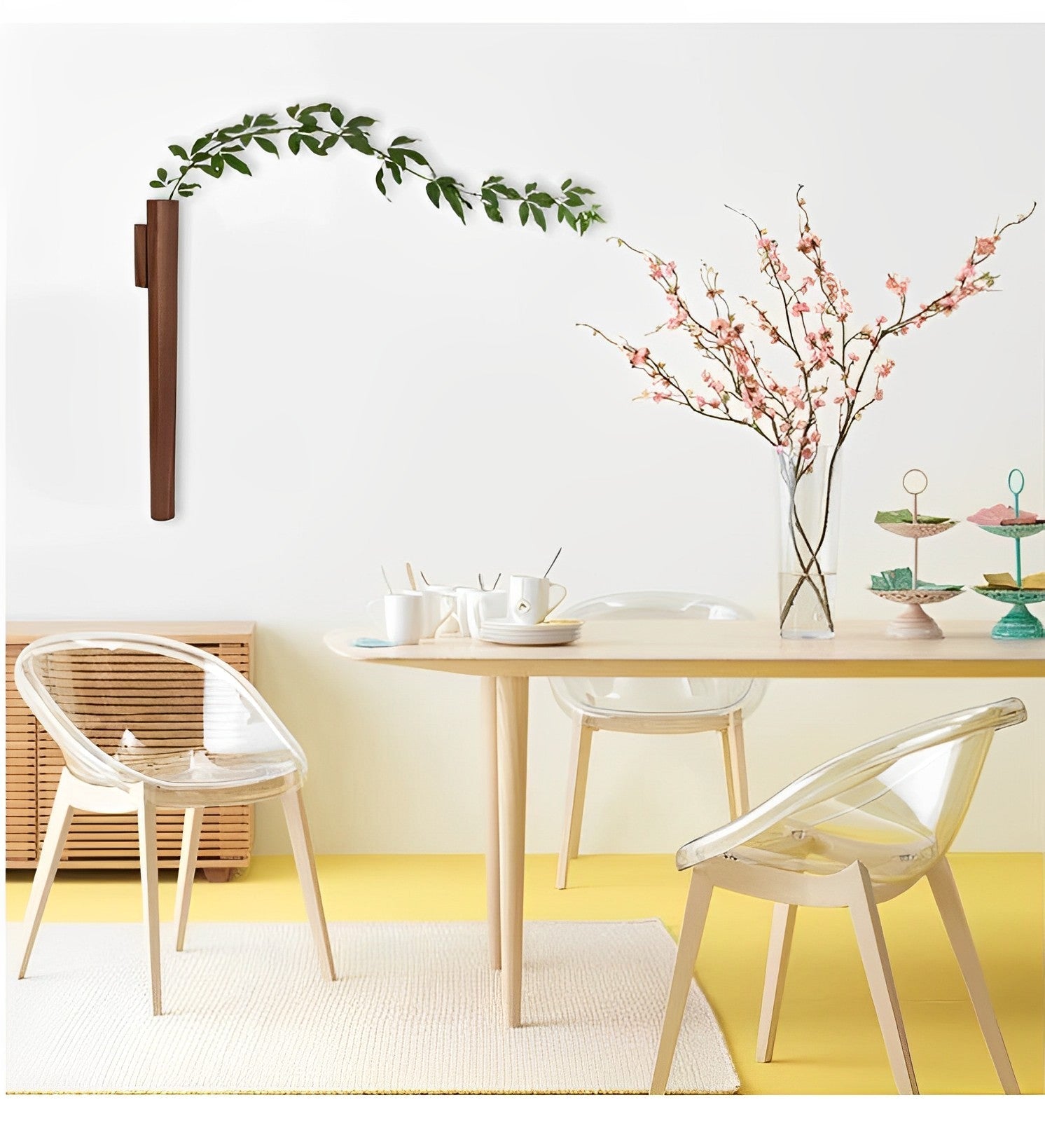 Beech wood wall vase holding tulip and wildflowers on pale plaster wall with natural window light