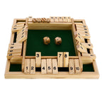 Two adults mid-game on Shut the Box wooden dice game with several numbered tiles flipped down on timber table