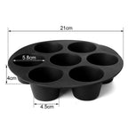 Seven freshly baked egg tarts in black silicone mould inside air fryer basket ready to serve