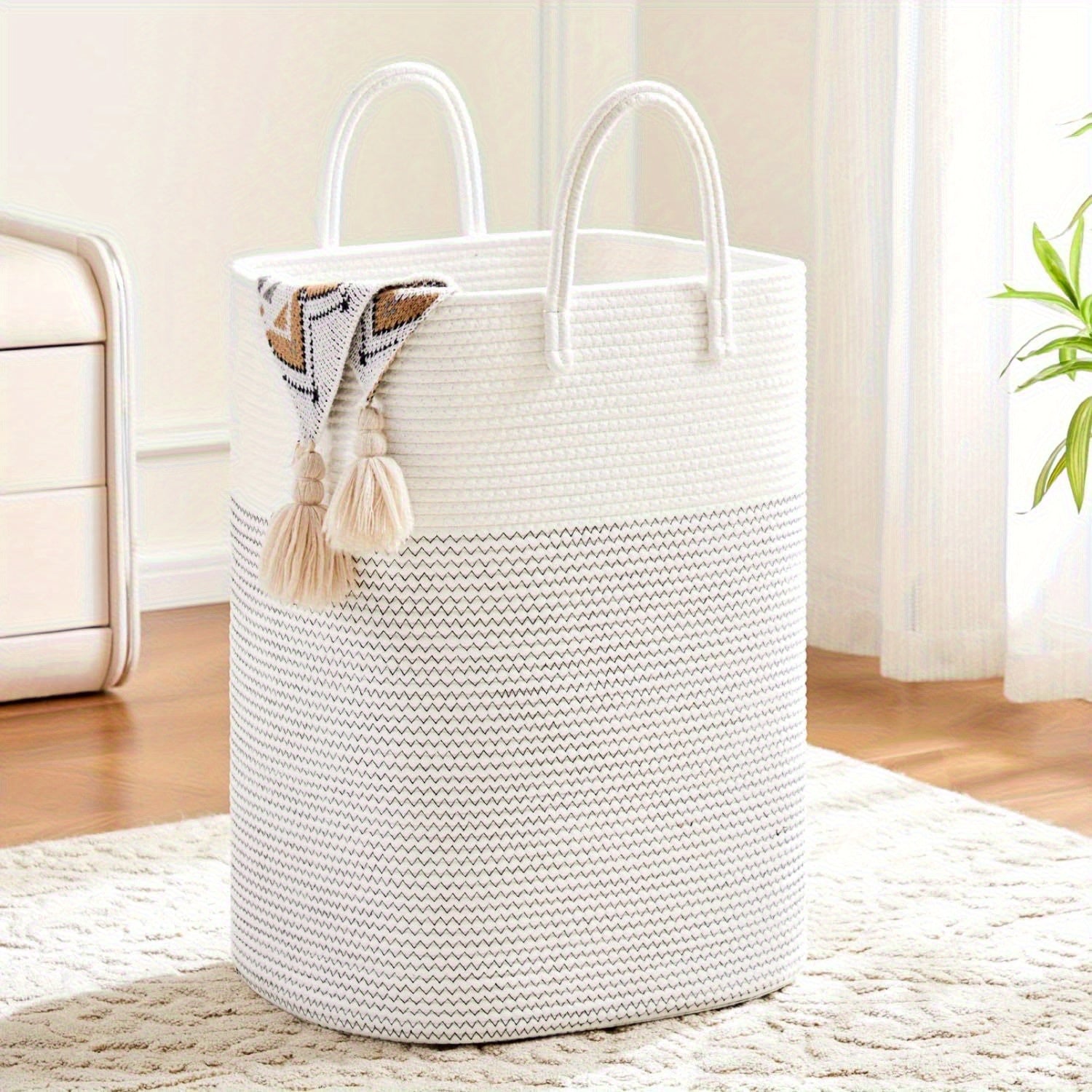 Woven cotton laundry basket 100L capacity shown in use filled with soft toys, braided handles visible, natural light setting