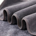 Four colour options of 18-piece towel set — blue grey white and red folded on marble surface