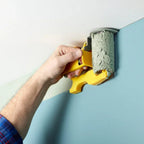 Freshly painted wall with clean edge at skirting board level, paint roller edger tool resting on drop sheet nearby