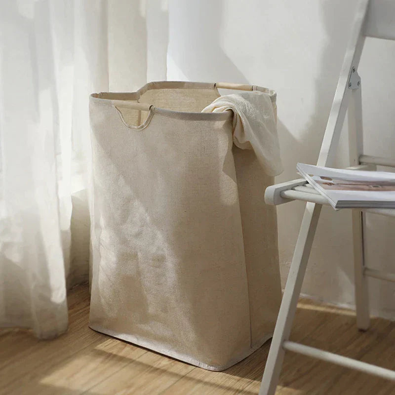 Wide bedroom interior with natural beige foldable laundry basket visible beside wardrobe, linen bedding in background
