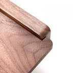 Close-up of walnut wood grain shelf surface of toilet roll holder, warm brown tones and natural wood texture visible