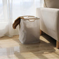 Close-up of smooth wooden carry handle on natural beige cotton-linen laundry basket showing texture detail