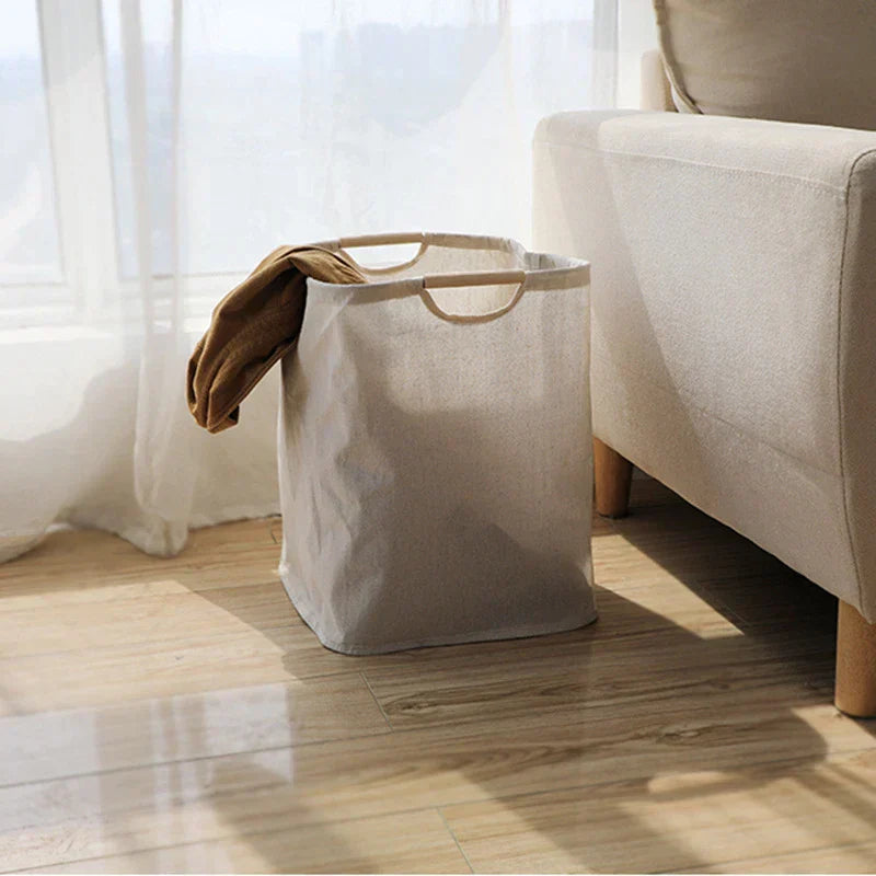 Close-up of smooth wooden carry handle on natural beige cotton-linen laundry basket showing texture detail