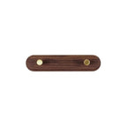 Close-up of brass knob hook on walnut wood coat rack rail showing smooth wood grain and brass finish