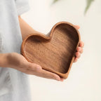 Close-up of smooth polished walnut wood grain on curved edge of heart-shaped snack bowl showing warm brown tones