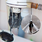 Stainless steel drain nozzle in use inside a pipe with high-pressure water jet clearing debris and blockage