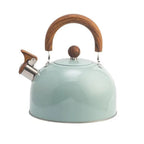 Three stovetop whistling kettles in white, light green, and black arranged on natural timber surface, colour variant overview