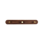 Hands installing beech wood coat rack on a white wall with mounting hardware and screwdriver