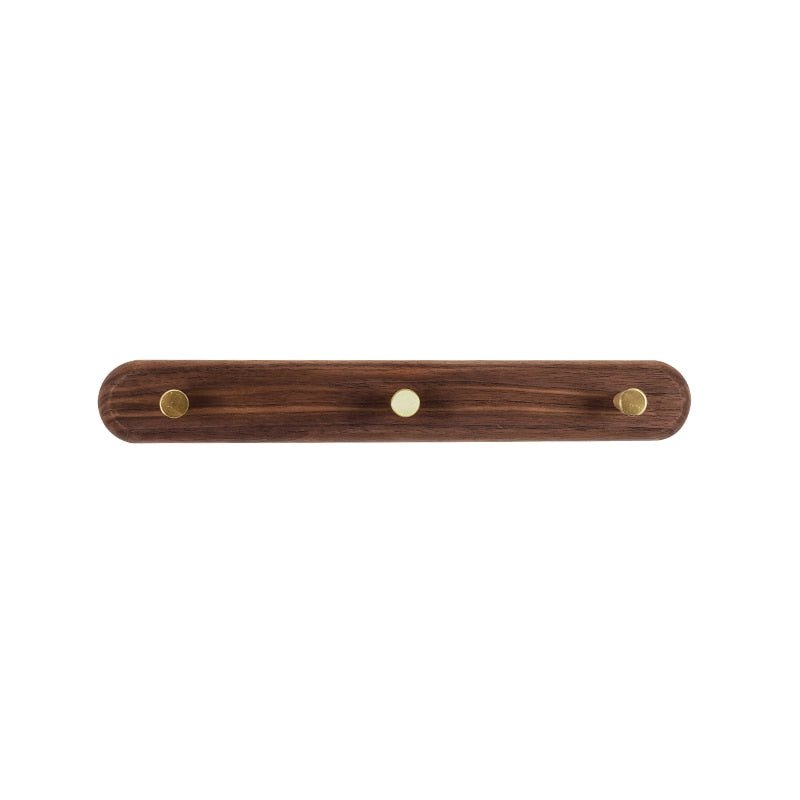 Hands installing beech wood coat rack on a white wall with mounting hardware and screwdriver