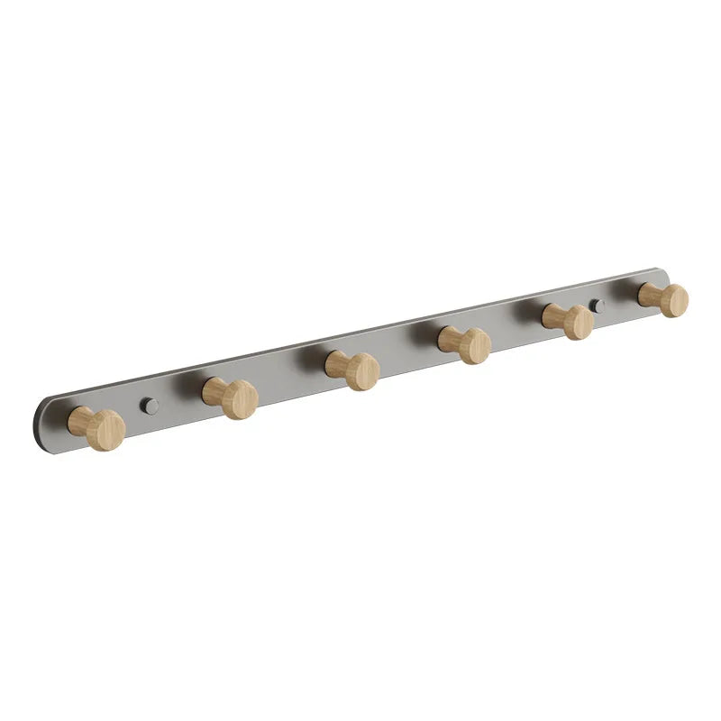 Hand hanging a knit scarf onto a wooden hook on a grey-base wall coat rack mounted on a wall