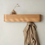 Under-shelf hooks on walnut coat rack with black coat and brown leather crossbody bag hanging neatly