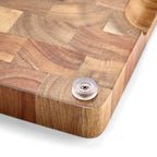 Person holding acacia wood cutting board by side grips showing easy transport handling feature