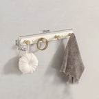White 5-hook wooden wall coat rack in bedroom corner with dressing gown and bag hanging, soft morning light