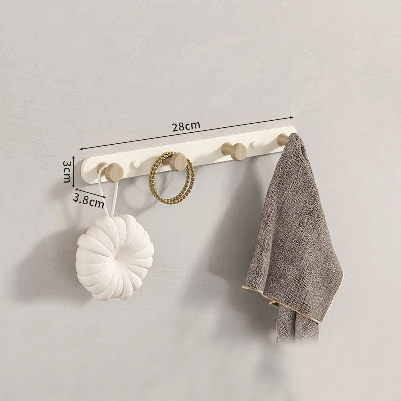White 5-hook wooden wall coat rack in bedroom corner with dressing gown and bag hanging, soft morning light